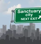 sanctuary city sign in front of a city skyline