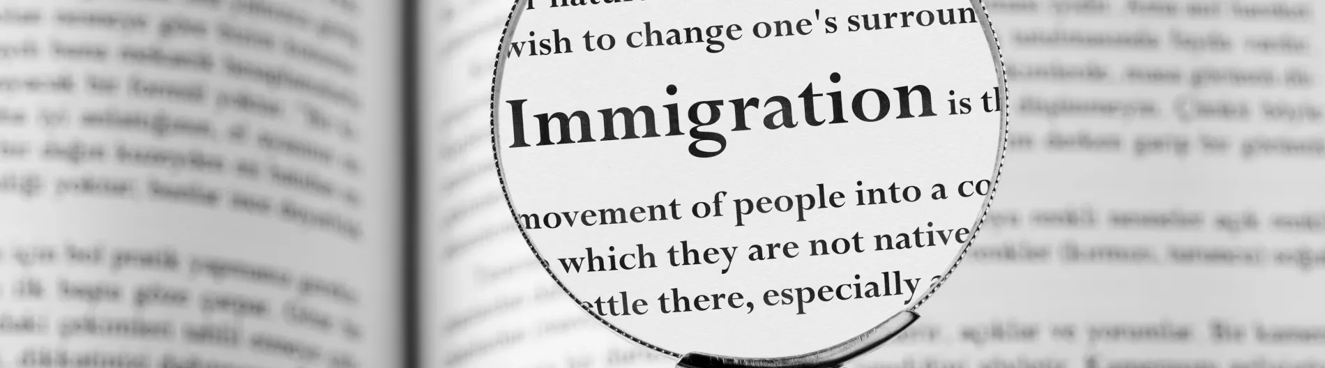 Dictionary with definition of immigration under a microscope