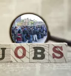 Magnifying Glass hovering over migrants, Block letters read as "Jobs"
