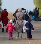 migrant woman and her young children walking