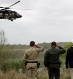 Three men saluting military helicopter