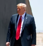 President Trump standing next to a black wall