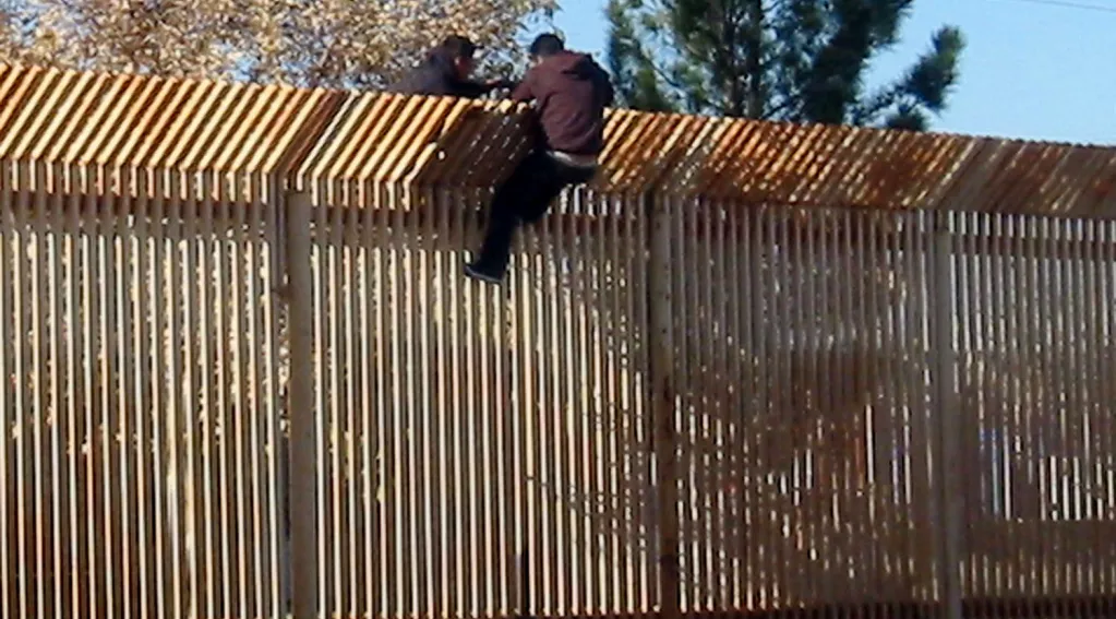 2 men scale border wall with Mexico