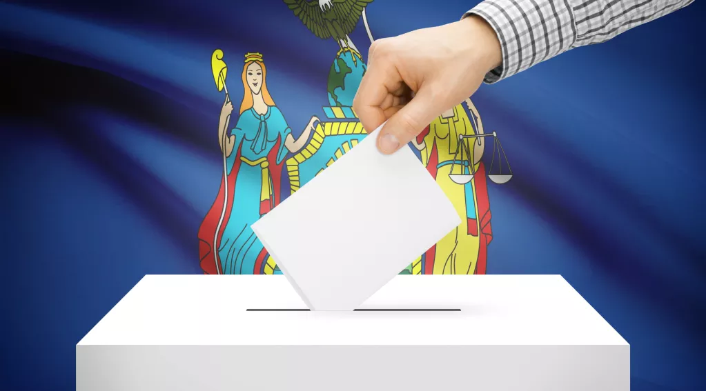 Hand putting card in ballot box with New York flag in the background