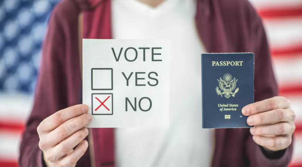 Man holding passport and a yes no sign with U.S. flag in the background