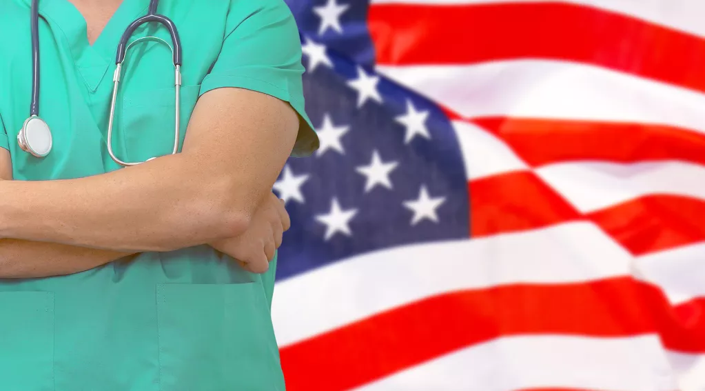 Doctor with stethoscope standing next to American flag